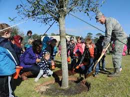 Children helping man plant tree
