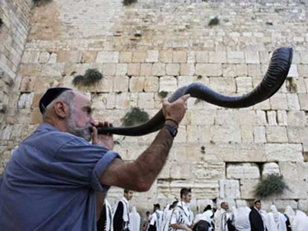 Man blowing the Shofar in front of the Western wall in Jerusalem.