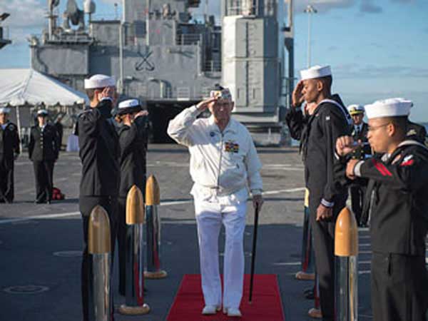 Survivor of D-Day attacks Captain Jack Evans salutes sailors on USS Pearl Harbor.