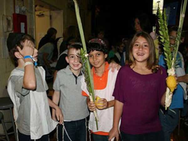 Children with squash and corn husks celebrating Shemini Atzeret.