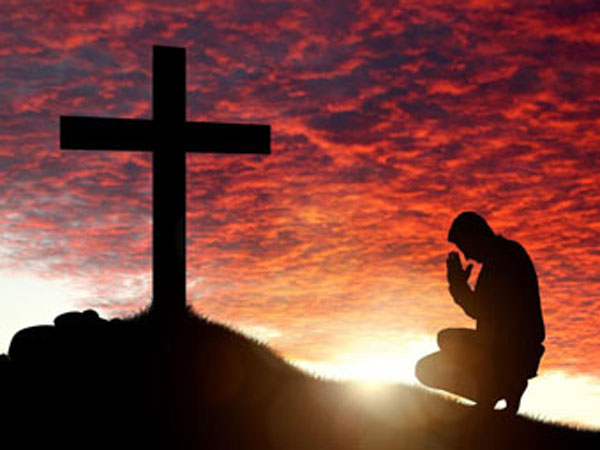 Man praying to cross during Lent.